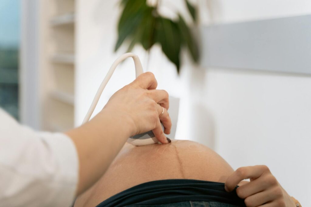 A close-up of a healthcare professional conducting an ultrasound on a pregnant woman.